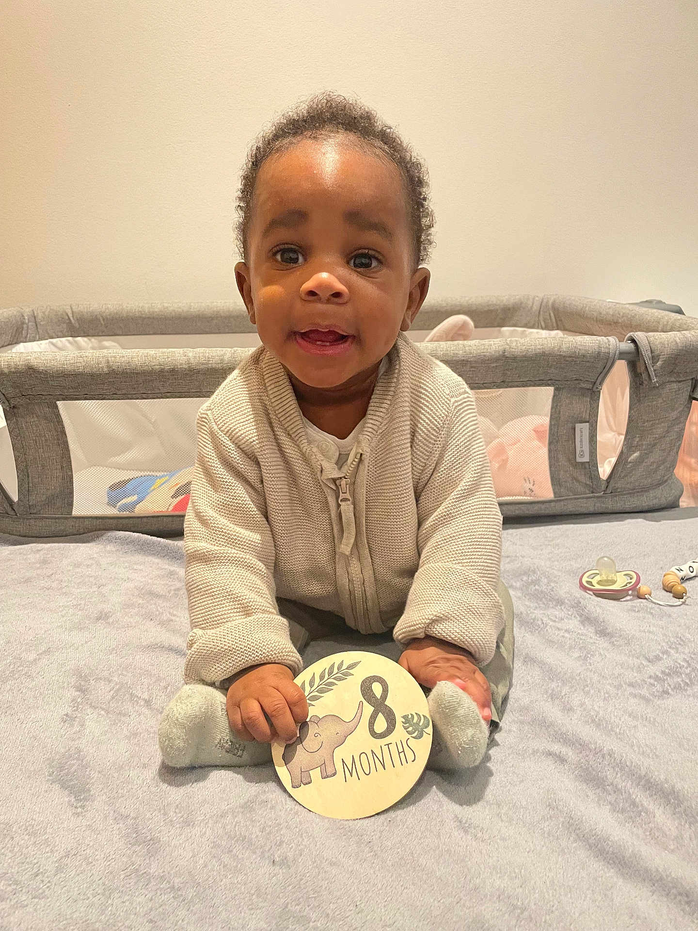 Aaron participe au concours pour gagner de l'argent avec cette photo : baby, infant, child, sitting, blanket, sign, elephant, months, clothing, socks, indoor, playpen, toy, curly_hair, smiling, cute, cozy, portrait, young_child, happy