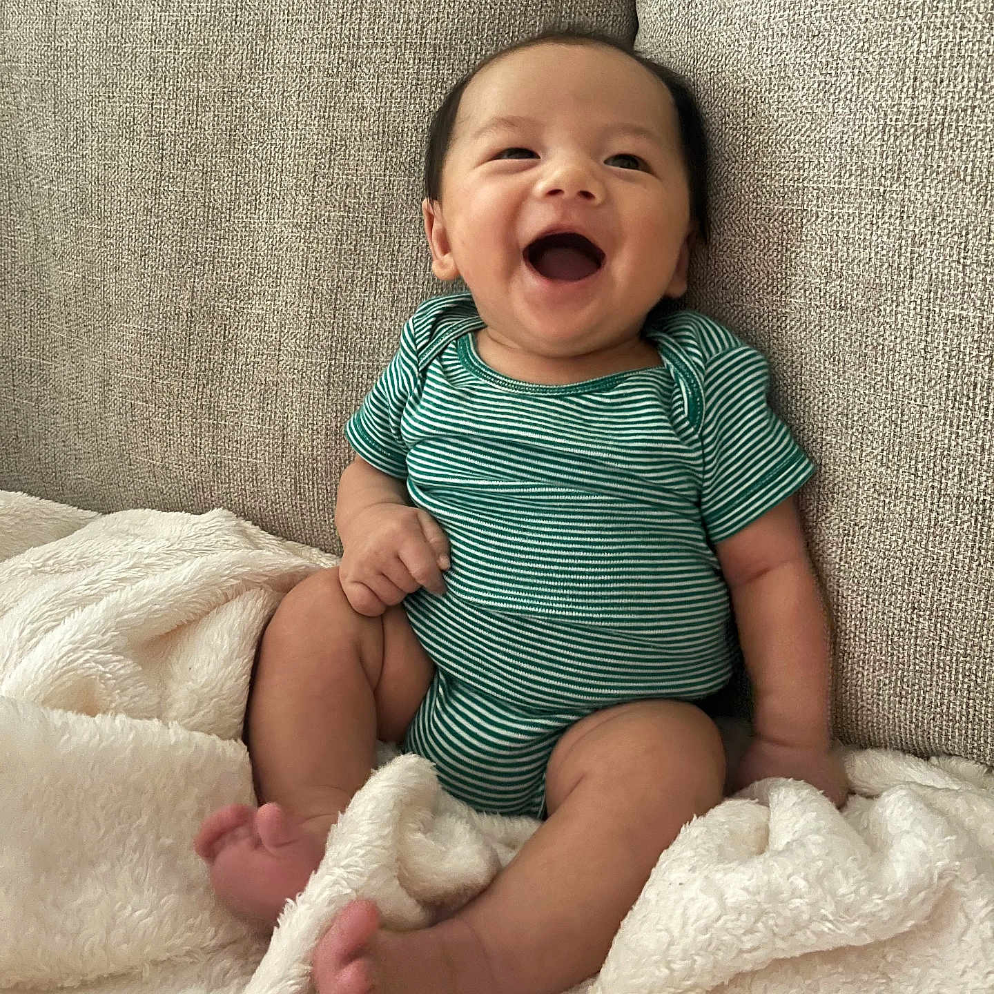 Vincent joined the competition — help win amazing prizes! baby, blanket, child, couch, cute, fabric, face, foot, hand, happy, indoors, infant, laughing, onesie, person, seated, skin, smiling, soft_texture, striped_clothing