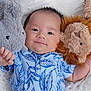 Vincent is registered to the contest to win money with this photo: baby, infant, smile, face, plush_toy, elephant_toy, lion_toy, blue_shirt, leaf_pattern, soft_blanket, cuddle, happy, cute, child, portrait, lying_down, hand, furry, comfort, indoor