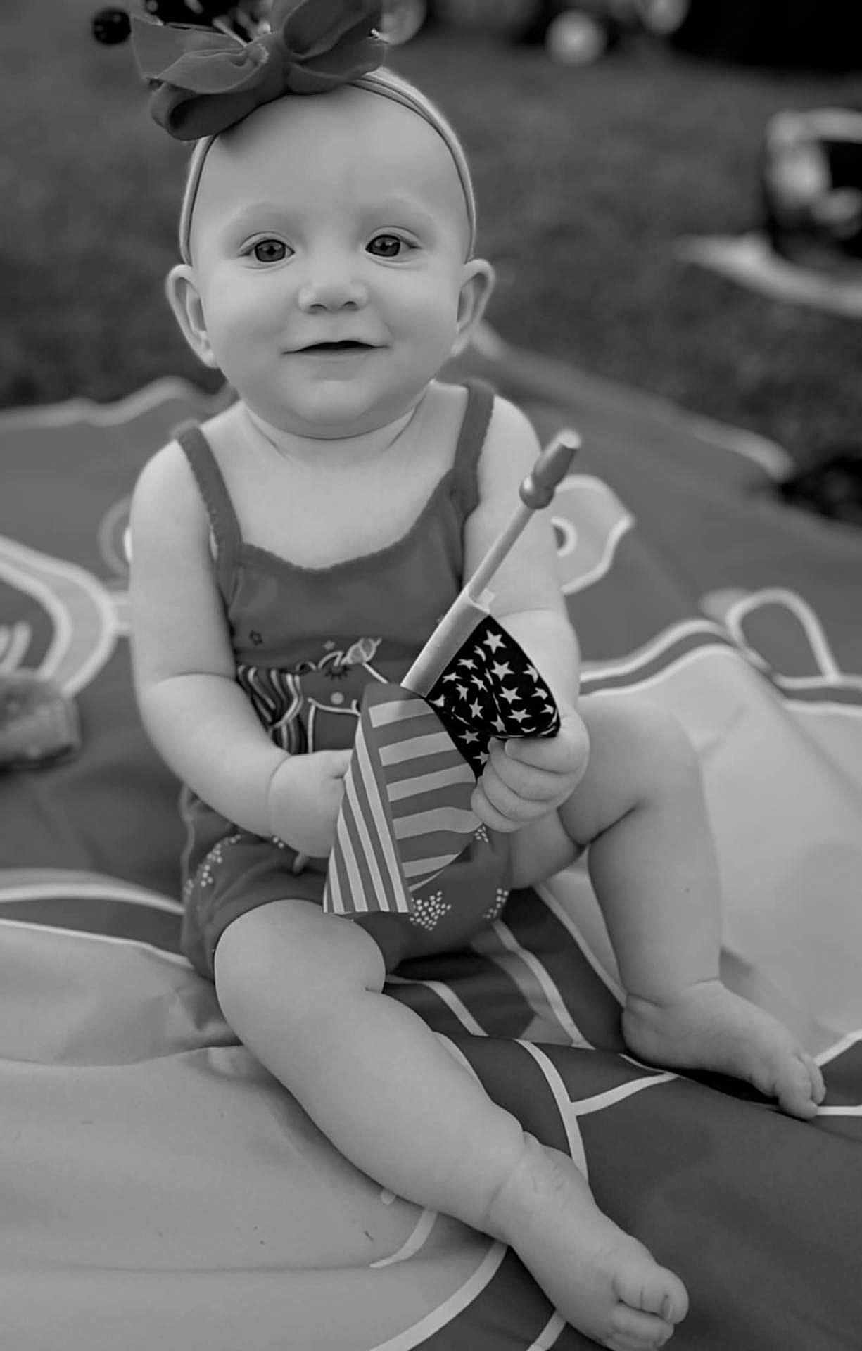 Lillian is registered to the contest to win money with this photo: baby, child, infant, headband, bow, flag, american_flag, outdoor, blanket, sitting, smile, cute, portrait, legs, hand, playful, monochrome, grass, summer, happy
