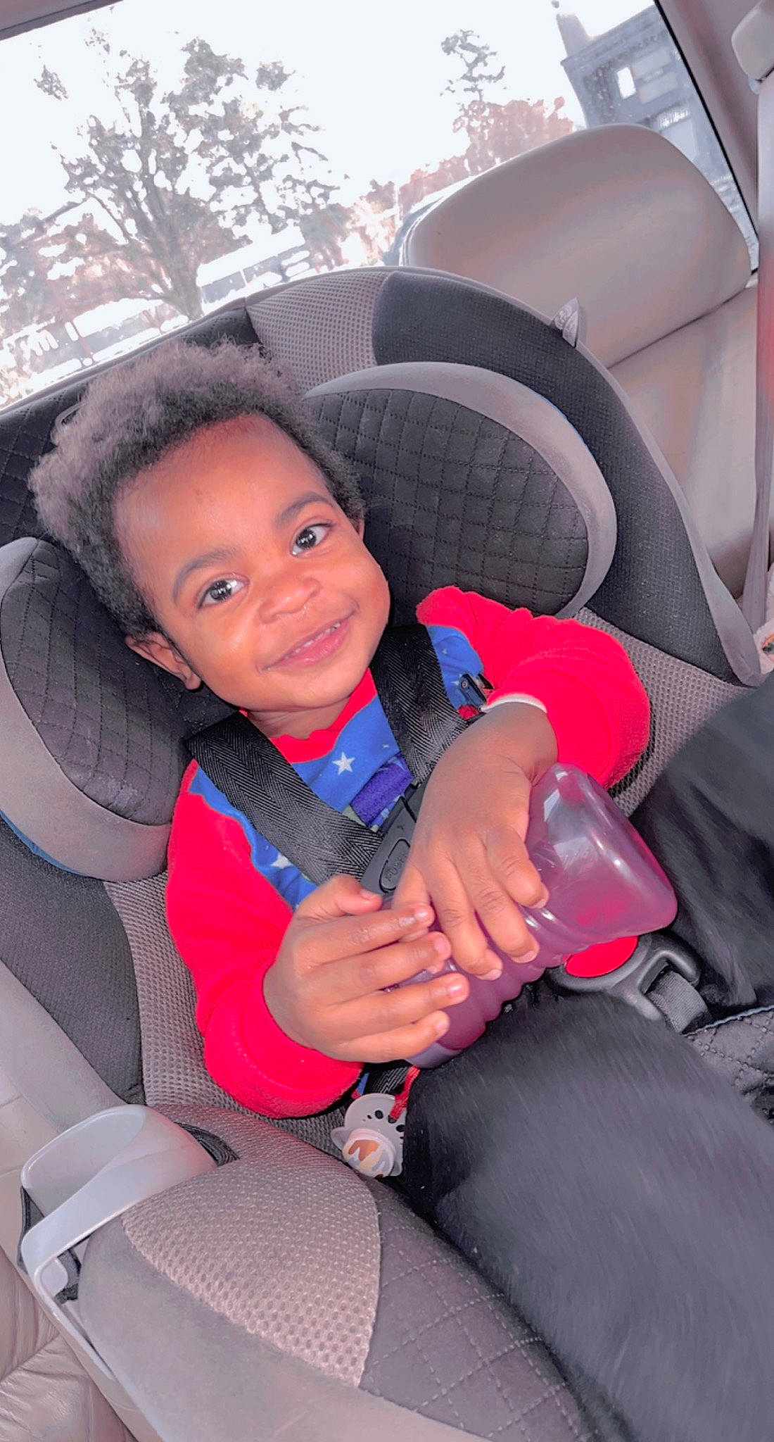 Jayceon is registered to the contest to win money with this photo: auto_part, automotive_design, automotive_exterior, car, car_seat, car_seat_cover, comfort, fun, happy, head_restraint, joy, motor_vehicle, person, plant, smile, steering_part, steering_wheel, toddler, tree, vehicle