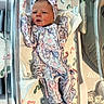 newborn, baby, infant, hospital, bassinet, blanket, footprints, floral_clothing, headband, swaddle, sleeping, person, cute, indoors, child, newborn_clothing, hospital_bassinet, soft_lighting, portrait, baby_gear