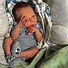newborn, baby, infant, child, portrait, lying_down, onesie, striped_clothing, blanket, green_blanket, plush_toy, stuffed_animal, crib, cushion, indoor, bedroom, sleeping_area, hand_gesture, face, photography