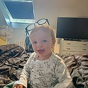 Esteban a rejoint le concours — aidez-le/la à gagner de superbes lots ! bed, blanket, casual, child, clothing, cute, fan, furniture, glasses, happy, home, indoor, person, portrait, room, sitting, smile, television, toddler, young_child