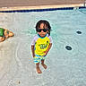 child, pool, sunglasses, water, rash_guard, shorts, barefoot, turtle_sculpture, outdoor, summer, playful, confident, water_park, swimwear, kid, person, recreation, sunny, fun, vacation