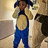 child, costume, sonic_the_hedgehog, blue, beige, couch, indoor, mirror, wall, sock, person, furniture, standing, portrait, room, soft_lighting, fabric, clothing, expression, home