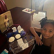 Brandon is registered to the contest to win money with this photo: child, smile, cupcakes, candles, number_36, table, chair, framed_photo, light, window, hair, frosting, container, birthday, celebration, room, person, indoor, shadow, face