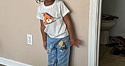 Brandon is registered to the contest to win money with this photo: child, smiling, standing, indoor, tshirt, jeans, teddy_bear, wall, floor, doorway, bathroom, tile_floor, wood_floor, black_shoes, happy, person, casual_clothing, young_child, hair, home