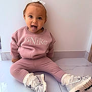Victoire a rejoint le concours — aidez-le/la à gagner de superbes lots ! child, toddler, pink_clothing, nike, sneakers, white_bow, tongue_out, playful, sitting, floor, tile_floor, indoor, cute, happy, person, portrait, long_sleeves, leggings, white_socks, young_child