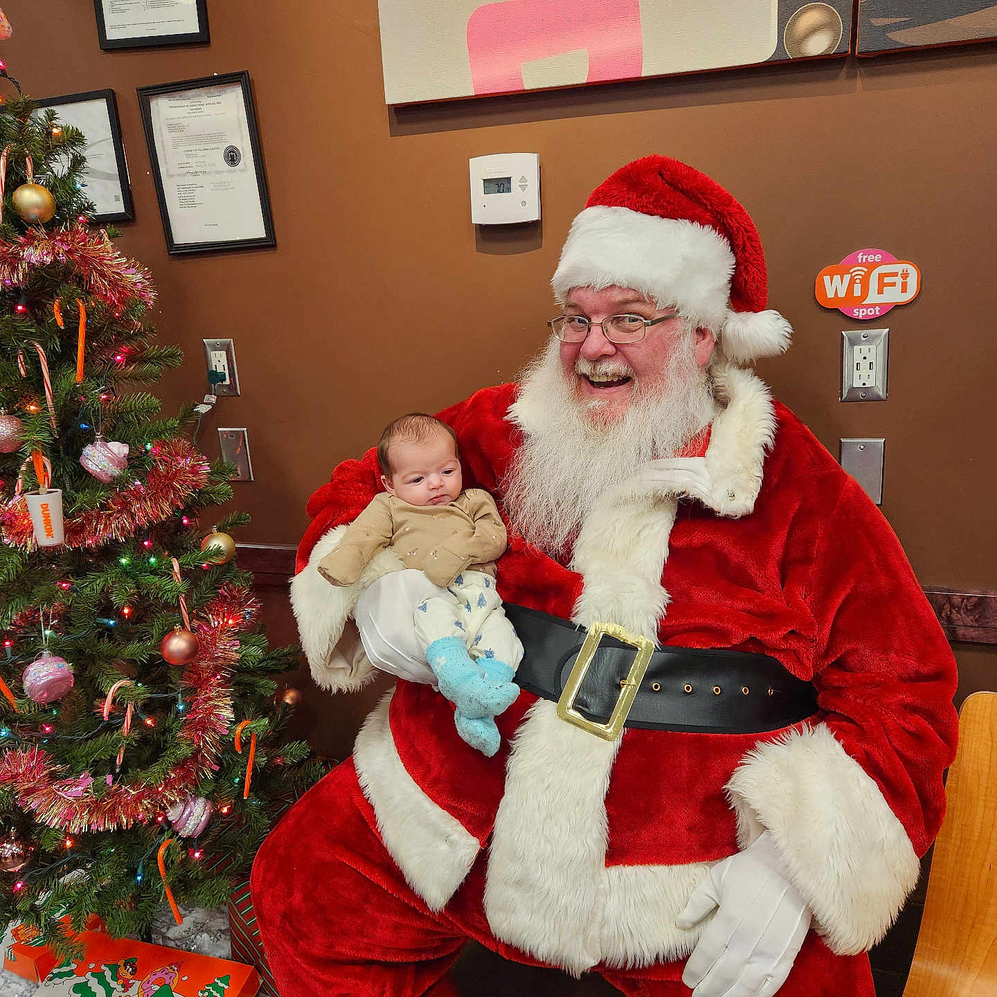 Sophia joined the competition — help win amazing prizes! baby, candy_cane, celebration, child, christmas_tree, decorations, festive, gift_box, glasses, holiday, indoor, person, red_suit, santa_claus, smiling, wall_art, warm_lighting, white_beard, wifi_sign, wooden_chair