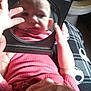 baby, child, mirror, reflection, pink_clothing, hand, face, indoors, blanket, pattern, curious, portrait, infant, person, closeup, baby_clothes, holding, looking, seat, home