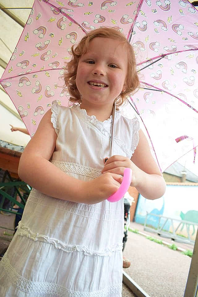 Clara participe au concours pour gagner de l'argent avec cette photo : arm, child, day, dress, facial_expression, girl, hair, human_hair_color, infant, joy, leg, material, person, pink, shoulder, sitting, skin, smile, standing, textile