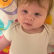 Nova joined the competition — help win amazing prizes! baby, infant, child, toddler, face, eyes, hair, clothing, onesie, playmat, colorful, animal_design, smile, cute, lying_down, indoors, soft_lighting, skin, expression, portrait