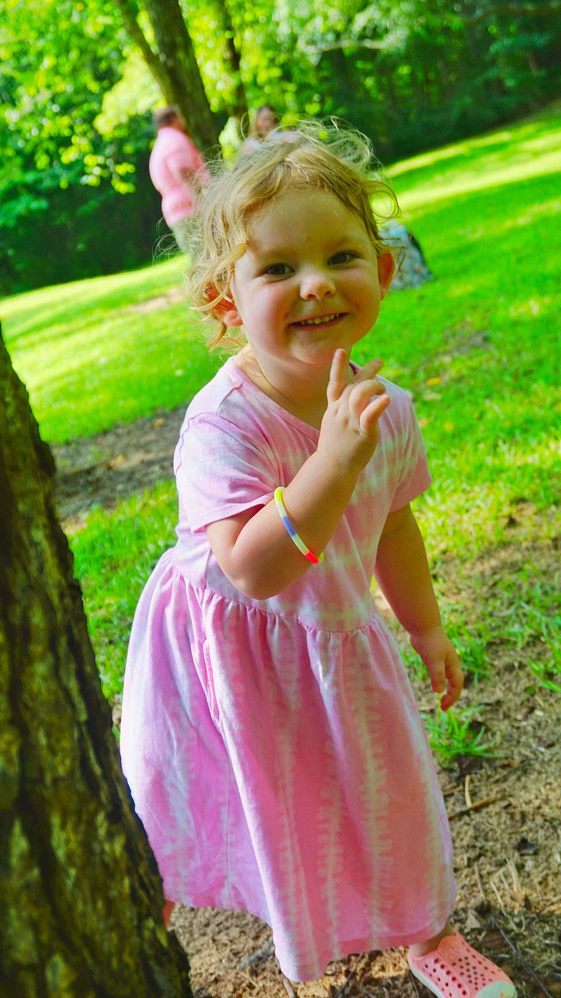 Payton is registered to the contest to win money with this photo: baby_toddler_clothing, botany, dress, fun, gesture, grass, green, happy, joy, leaf, leisure, nature, people_in_nature, person, photograph, pink, plant, smile, summer, sunlight