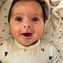 adorable, baby, blanket, child, closeup, cute, eyes, face, hair, happy, heart_pattern, indoors, infant, lying_down, mouth_open, onesie, pacifier, skin, smiling, soft_texture