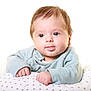 baby, blue_clothing, child, chubby_cheeks, closeup, curious_eyes, cute, face, hands, indoors, infant, pillow, portrait, resting, smiling, soft_lighting, star_pattern, tongue, white_background, young