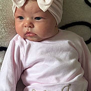 Lila-Jane is registered to the contest to win money with this photo: baby, blanket, bow, cheeks, child, clothing, cute, expression, face, hand, headband, indoor, infant, newborn, person, pink_clothing, portrait, resting, soft_texture, young_child