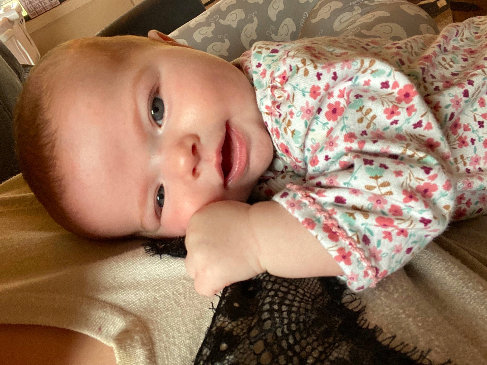 Harper is registered to the contest to win money with this photo: arm, baby, baby_toddler_clothing, cheek, child, comfort, eyelash, flooring, hand, human_body, iris, lip, nose, pattern, person, sitting, skin, sleeve, smile, toddler