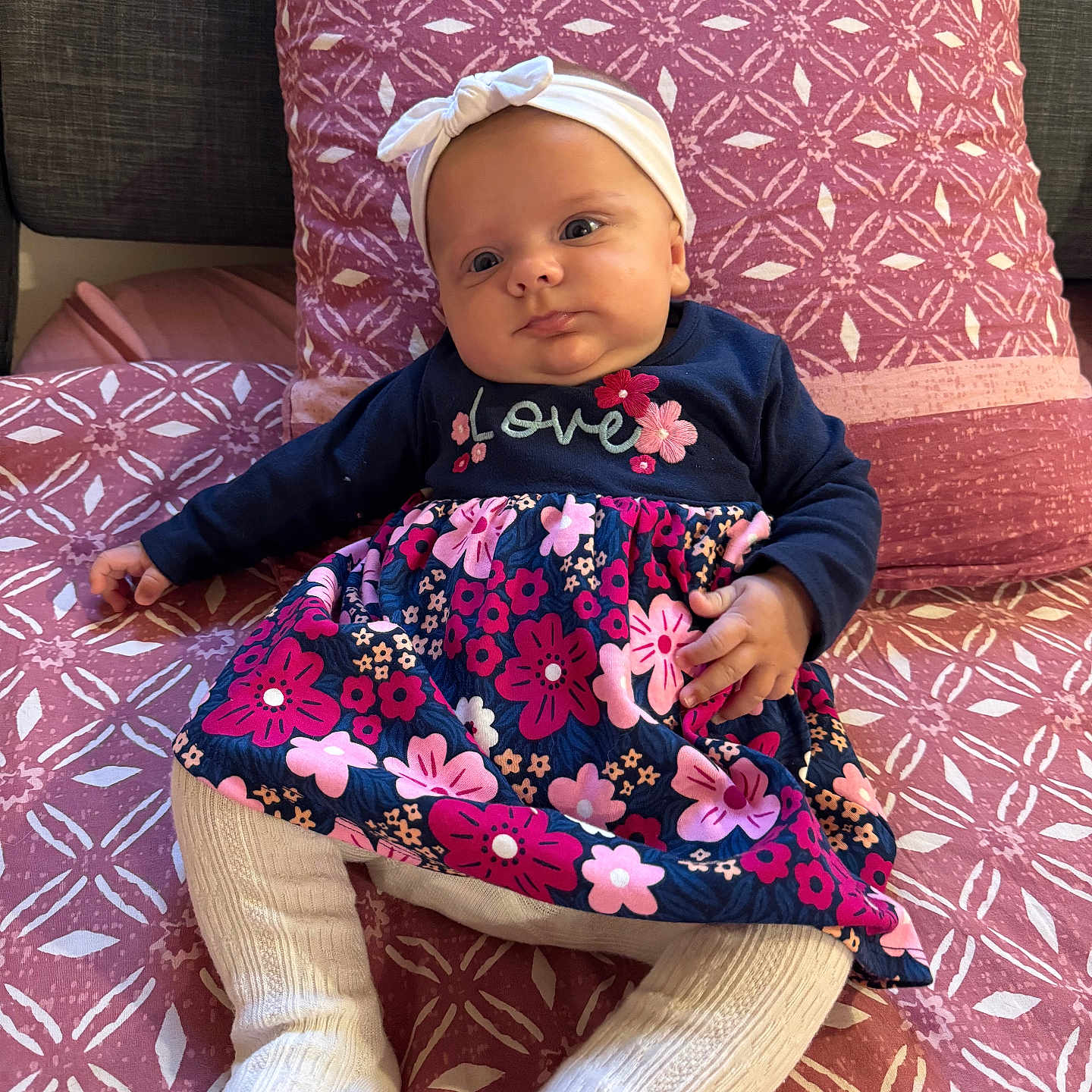 Emma participe au concours pour gagner de l'argent avec cette photo : baby, blanket, bonnet, clothing, couch, cushion, dress, face, furniture, hat, head, homedecor, pants, person, photography, pillow, portrait, purple, quilt, sitting