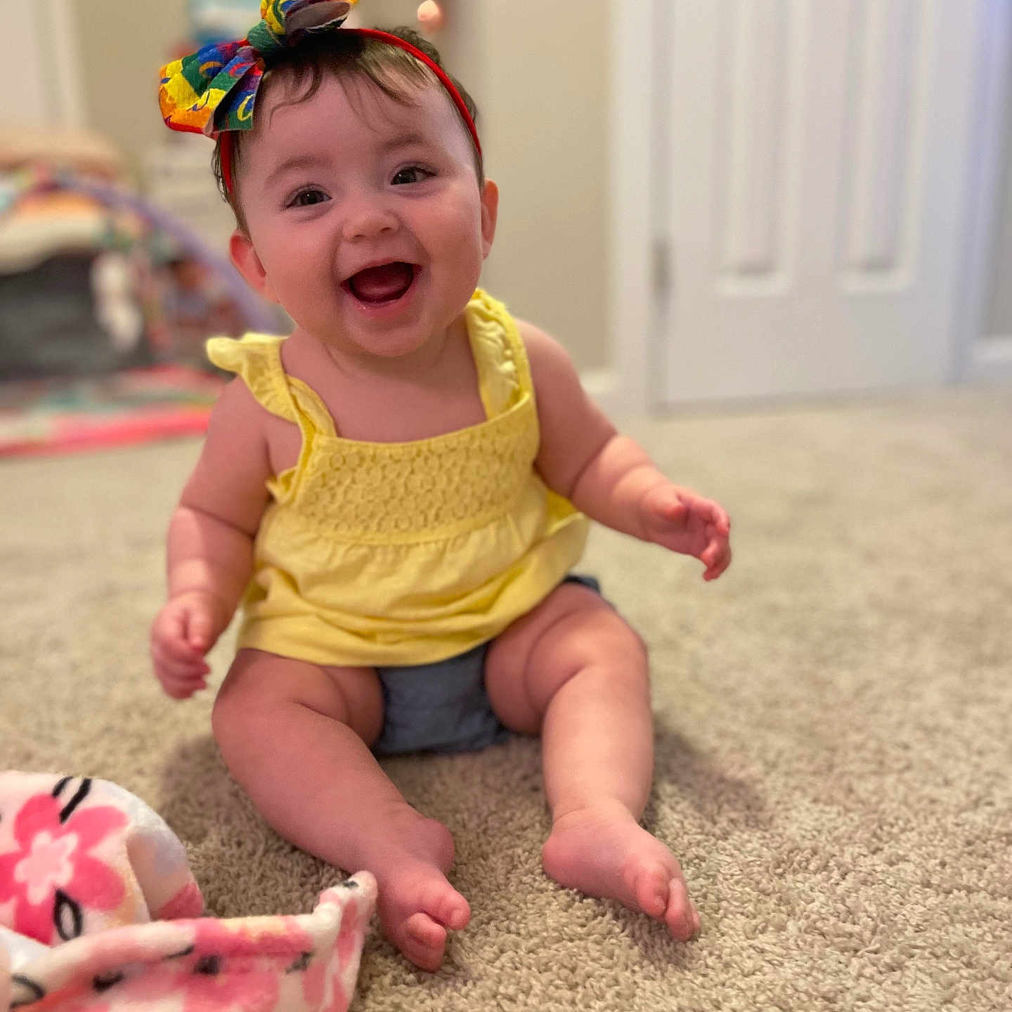 Lydia is registered to the contest to win money with this photo: accessories, baby, clothing, costume, door, dress, face, happy, head, indoors, laughing, pants, person, photography, plant, portrait, pottedplant, sitting, smile, t_shirt