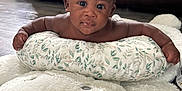 Jaylen is registered to the contest to win money with this photo: baby, infant, child, face, eyes, pillow, cushion, plush_toy, teddy_bear, floor, living_room, sofa, wood_floor, curly_hair, skin, expression, person, indoor, cute, young