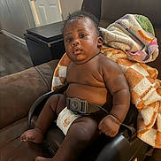 Jaylen joined the competition — help win amazing prizes! baby, infant, child, diaper, baby_seat, blanket, couch, furniture, indoor, person, seatbelt, living_room, curious, chubby, sitting, black_skin, expression, home, soft_lighting, casual