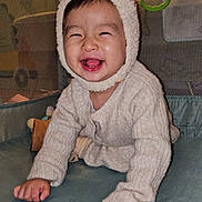 Huynh a rejoint le concours — aidez-le/la à gagner de superbes lots ! baby, child, smiling, crawling, hat, bear_ears, sweater, playpen, indoors, cute, happy, face, person, infant, childhood, cozy, warm_clothing, hands, tongue, joy
