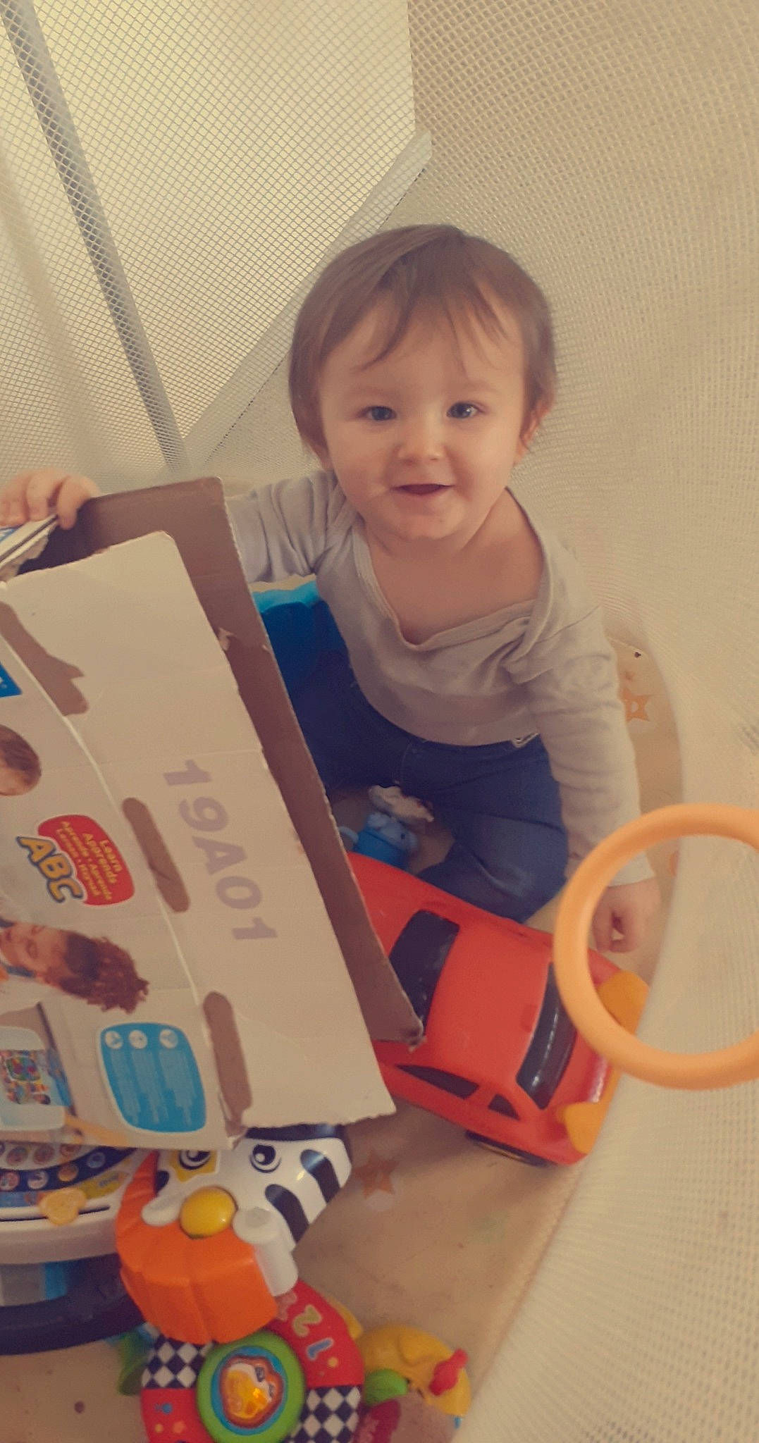 Djülyan a rejoint le concours — aidez-le/la à gagner de superbes lots ! baby, baby_products, baby_toddler_clothing, baby_toys, box, cardboard, carton, child, event, fun, packaging_and_labeling, paper_product, person, plastic, play, room, sitting, sleeve, smile, t_shirt