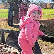Gracie joined the competition — help win amazing prizes! baby, cap, clothing, coat, face, grass, hat, head, jacket, machine, nature, outdoors, pants, person, photography, plant, portrait, sitting, tire, wheel