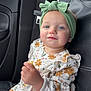 toddler, child, car_seat, headband, blue_eyes, snack, floral_outfit, ruffles, rosy_cheeks, soft_lighting, car_interior, seatbelt, black_leather, curious_expression, sitting, portrait, indoor, person, cute, young_child