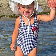 Emma is registered to the contest to win money with this photo: toddler, child, water, swimsuit, hat, sun_hat, holding_hand, beach, outdoor, summer, playground, sand, smiling, person, sunny, nature, trees, water_reflection, minnie_mouse, happy