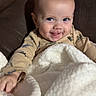 Koen joined the competition — help win amazing prizes! baby, blanket, brown_couch, child, smiling, blue_eyes, fluffy, happy, indoors, infant, person, cute, warm, cozy, clothing, face, head, hand, portrait, seated