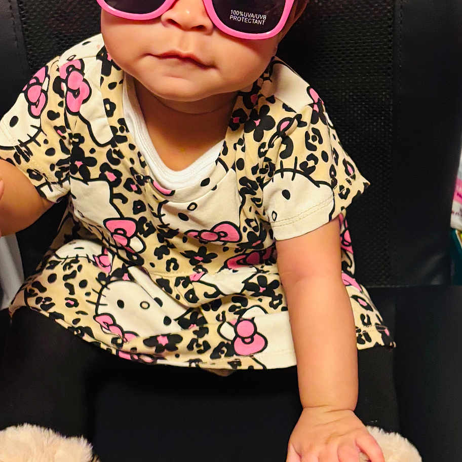 Kailani joined the competition — help win amazing prizes! accessory, baby, black_chair, boots, child, cute, fashion, fun, fuzzy_boots, headband, hello_kitty, indoor, patterned_clothing, person, pink_bow, portrait, sitting, stylish, sunglasses, toddler