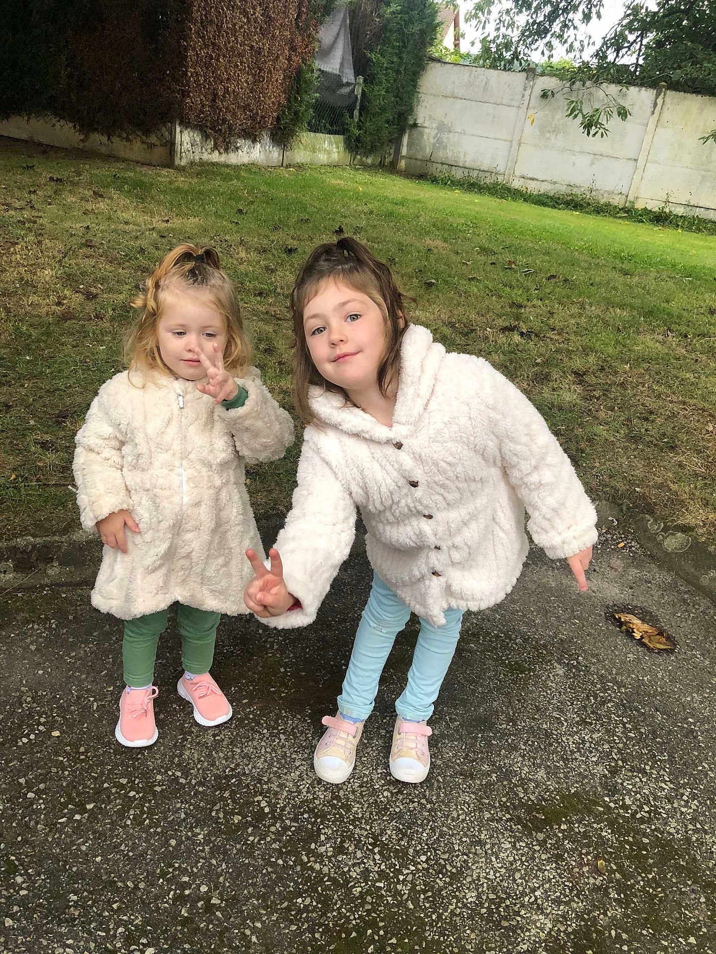 Helena Fortier a rejoint le concours — aidez-le/la à gagner de superbes lots ! child, children, outdoor, grass, backyard, coat, white_coat, peace_sign, playful, cute, two_children, sneakers, greenery, fence, happy, smile, person, casual_clothing, fall, young_kids
