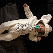 Dandre joined the competition — help win amazing prizes! baby, blanket, child, clothing, cute, dark_background, elephant_design, expression, face, footed_pajamas, hood, indoor, infant, lying_down, onesie, pacifier, portrait, small_hands, soft, warm