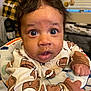 baby, child, onesie, football_pattern, messy_face, wide_eyes, curious, indoor, person_in_background, plaid_shirt, home, window_blinds, baby_seat, hand, face, closeup, expression, infant, clothing, soft_lighting
