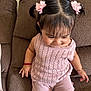 toddler, child, girl, hairclips, pink_clothing, knitwear, shorts, sitting, couch, brown_couch, indoors, bracelet, red_bracelet, happy, cute, portrait, home, smiling, young_child, casual