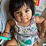 Lindsay Reyes is registered to the contest to win money with this photo: baby, child, infant, face, dark_hair, sitting, baby_seat, colorful, animal_print, toddler, cute, portrait, indoors, clothing, bracelet, expression, looking_at_camera, reflection, playful, close_up