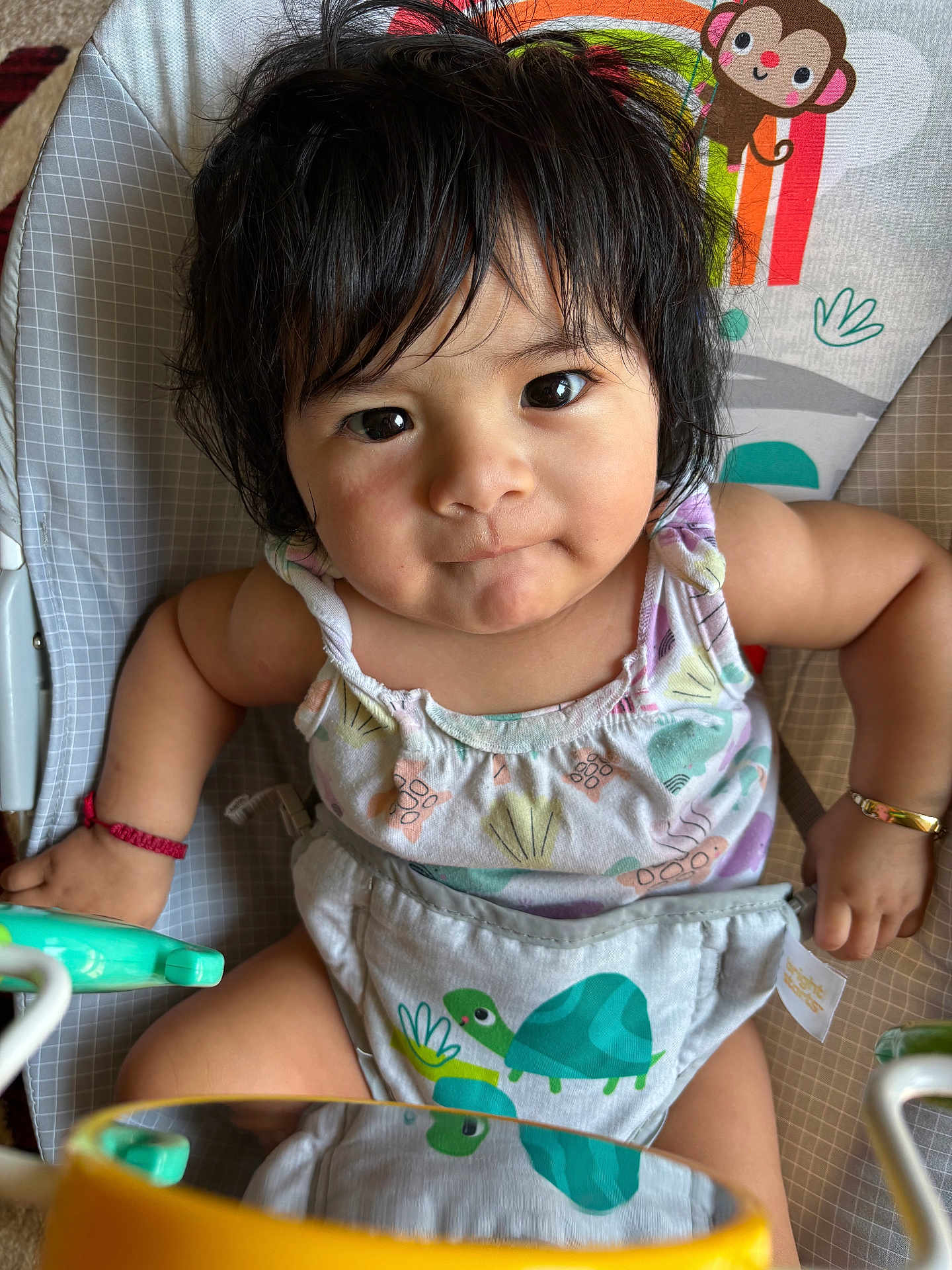 Lindsay Reyes is registered to the contest to win money with this photo: baby, child, infant, face, dark_hair, sitting, baby_seat, colorful, animal_print, toddler, cute, portrait, indoors, clothing, bracelet, expression, looking_at_camera, reflection, playful, close_up