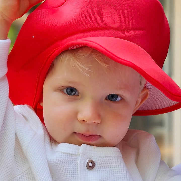 Liam participe au concours pour gagner de l'argent avec cette photo : baby, blonde_hair, blue_eyes, buttoned_shirt, casual_clothing, child, closeup, curious, cute, expression, face, hat, headwear, outdoor, person, portrait, red_hat, toddler, white_shirt, young_child