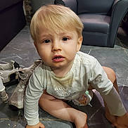 Liam participe au concours pour gagner de l'argent avec cette photo : barefoot, blonde_hair, blue_armchair, candid, casual, child, curious, diaper, expression, floor, furniture, hands, indoor, living_room, person, sneakers, tile_floor, toddler, white_shirt, young_child