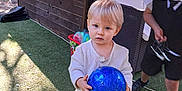 Liam participe au concours pour gagner de l'argent avec cette photo : backyard, blue_ball, casual_clothing, child, curious, daylight, fence, grass, nature, outdoor, person, play, shoes, soccer_ball, sunlight, toddler, toy, trees, wicker_chair, young_child