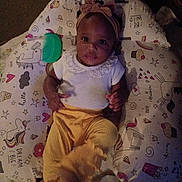 Carmen is registered to the contest to win money with this photo: baby, child, infant, headband, yellow_pants, cushion, unicorn, toy, comb, cute, lying_down, indoors, colorful, patterned, clothing, portrait, young_child, relaxing, person, soft_fabric