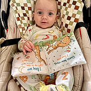Konstantin is registered to the contest to win money with this photo: baby, infant, seat, cushion, fabric_book, bunny, pajamas, slippers, animal_slippers, child, cute, indoors, smiling, face, hand, toy, soft_toy, patterned_fabric, colorful, closeup