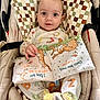 baby, infant, seat, cushion, fabric_book, bunny, pajamas, slippers, animal_slippers, child, cute, indoors, smiling, face, hand, toy, soft_toy, patterned_fabric, colorful, closeup