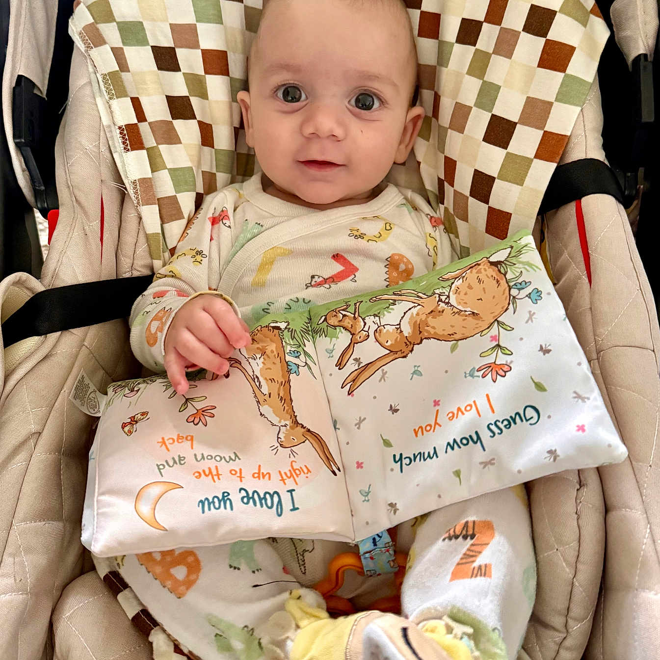Konstantin is registered to the contest to win money with this photo: animal_slippers, baby, bunny, child, closeup, colorful, cushion, cute, fabric_book, face, hand, indoors, infant, pajamas, patterned_fabric, seat, slippers, smiling, soft_toy, toy