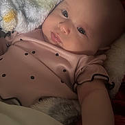 Luz Alaia is registered to the contest to win money with this photo: baby, infant, face, blanket, clothing, pink_outfit, dots, skin, arm, hand, lying_down, cozy, soft_texture, indoors, portrait, closeup, cute, child, newborn, resting