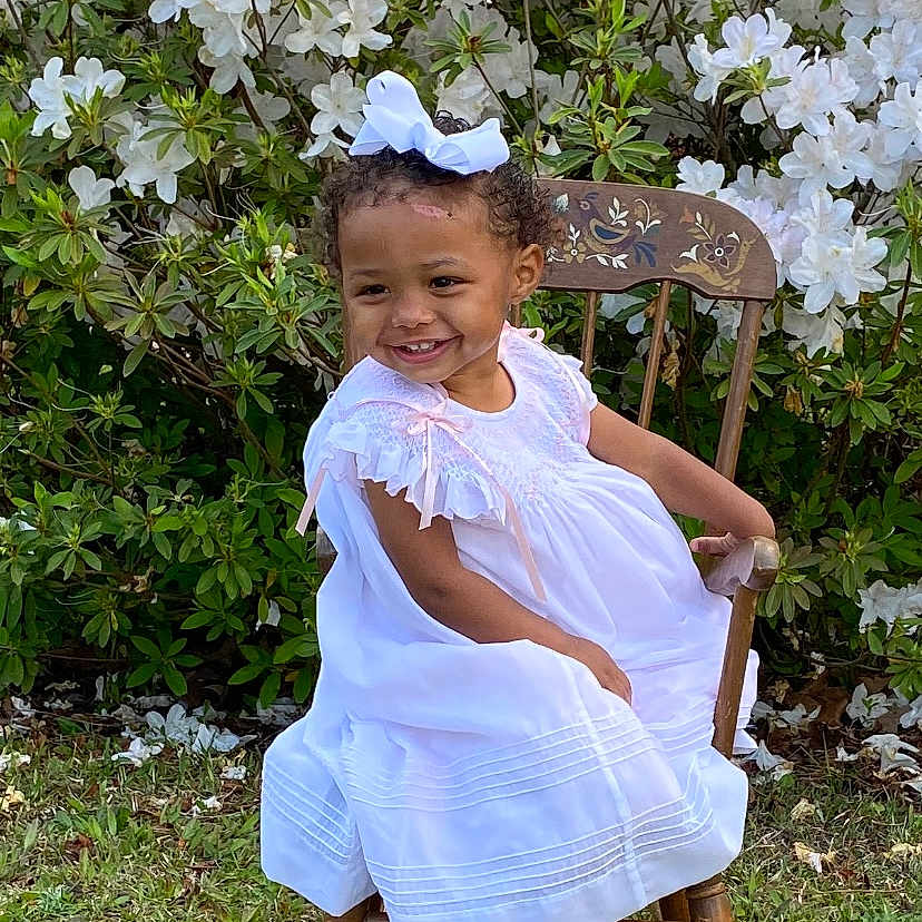 Sadie joined the competition — help win amazing prizes! backyard, child, clothing, dress, face, female, flower, furniture, girl, grass, head, nature, outdoors, person, petal, photography, plant, portrait, sitting, yard
