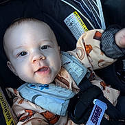 Hunter is registered to the contest to win money with this photo: baby, infant, child, car_seat, portrait, smiling, happy, face, eyes, mouth, blanket, clothing, harness, seatbelt, safety_strap, vehicle, indoor, close_up, patterned_fabric, photography