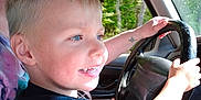 Jaxson joined the competition — help win amazing prizes! child, boy, steering_wheel, car_interior, adult_partial, sunglasses, window, trees, smiling, blue_eyes, blond_hair, hands, tattoo, dashboard, seat, portrait, daylight, road_trip, family, closeup